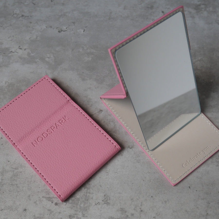 Compact pink Nodspark folding pocket mirror displayed open next to its matching pink textured protective pouch.