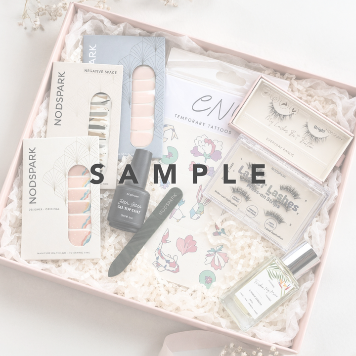 Curated beauty products grab bag featuring Nodspark nail wraps, temporary tattoos, press-on lashes, gel top coat, and hair mist.