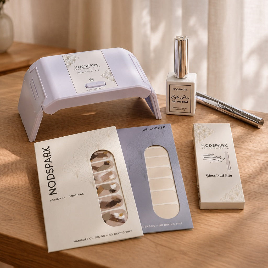 Nodspark Jelly Manicure Starter Kit featuring a lilac UV lamp, gel top coat, nail files, and nail wraps arranged on a soft surface.