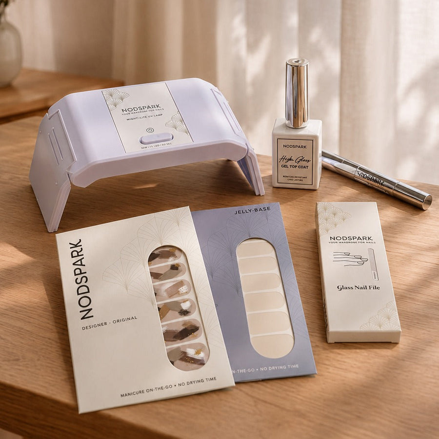 Nodspark Jelly Manicure Starter Kit featuring a lilac UV lamp, gel top coat, nail files, and nail wraps arranged on a soft surface.