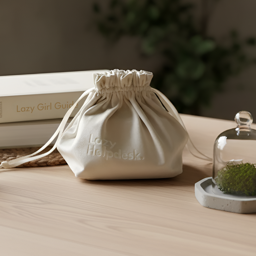 Off-white drawstring fabric pouch sitting on a wooden desk alongside home decor items.