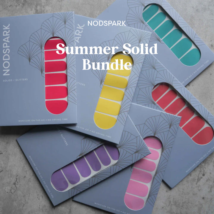 An assortment of colorful summer nail wrap packages arranged on a neutral surface.
