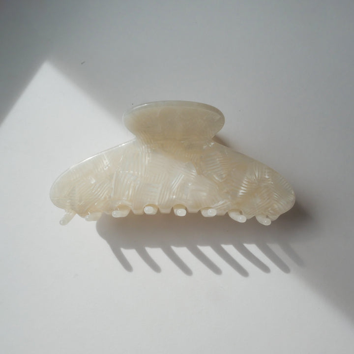 Milky white classic curved hair claw clip sitting upright on a plain white background.