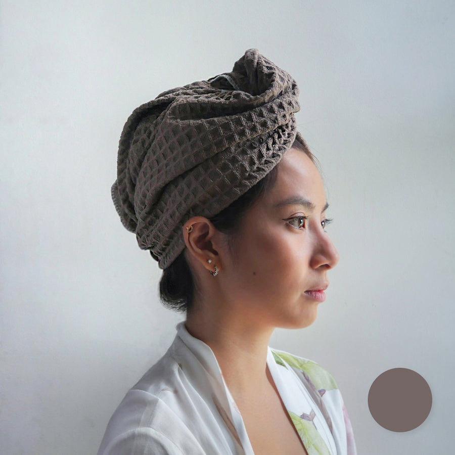 Woman wearing a brown twisted microfiber hair towel wrap, shown from a side profile.