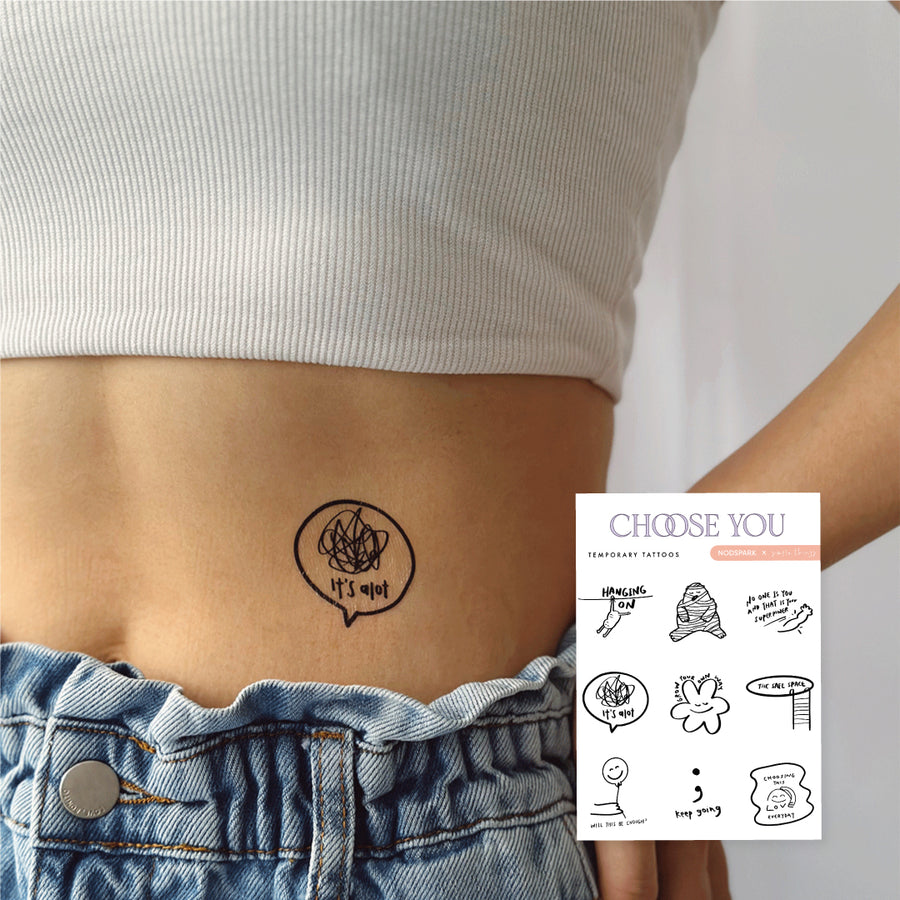 Person wearing a line-art temporary tattoo on their lower abdomen beside an inset image of the full Choose You tattoo sheet.